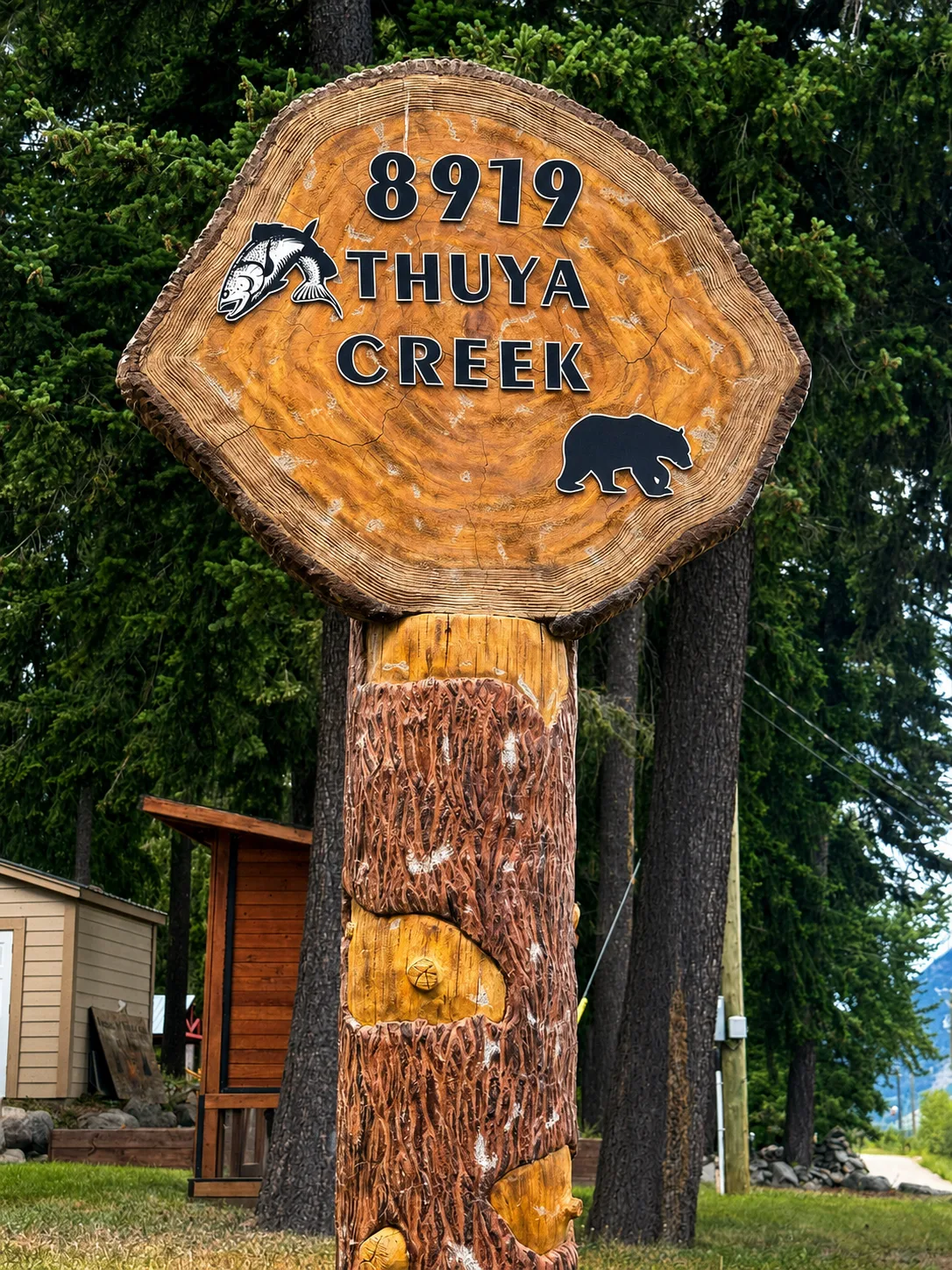 The carved 8919 Thuya Creek welcome sign with fish and bear
