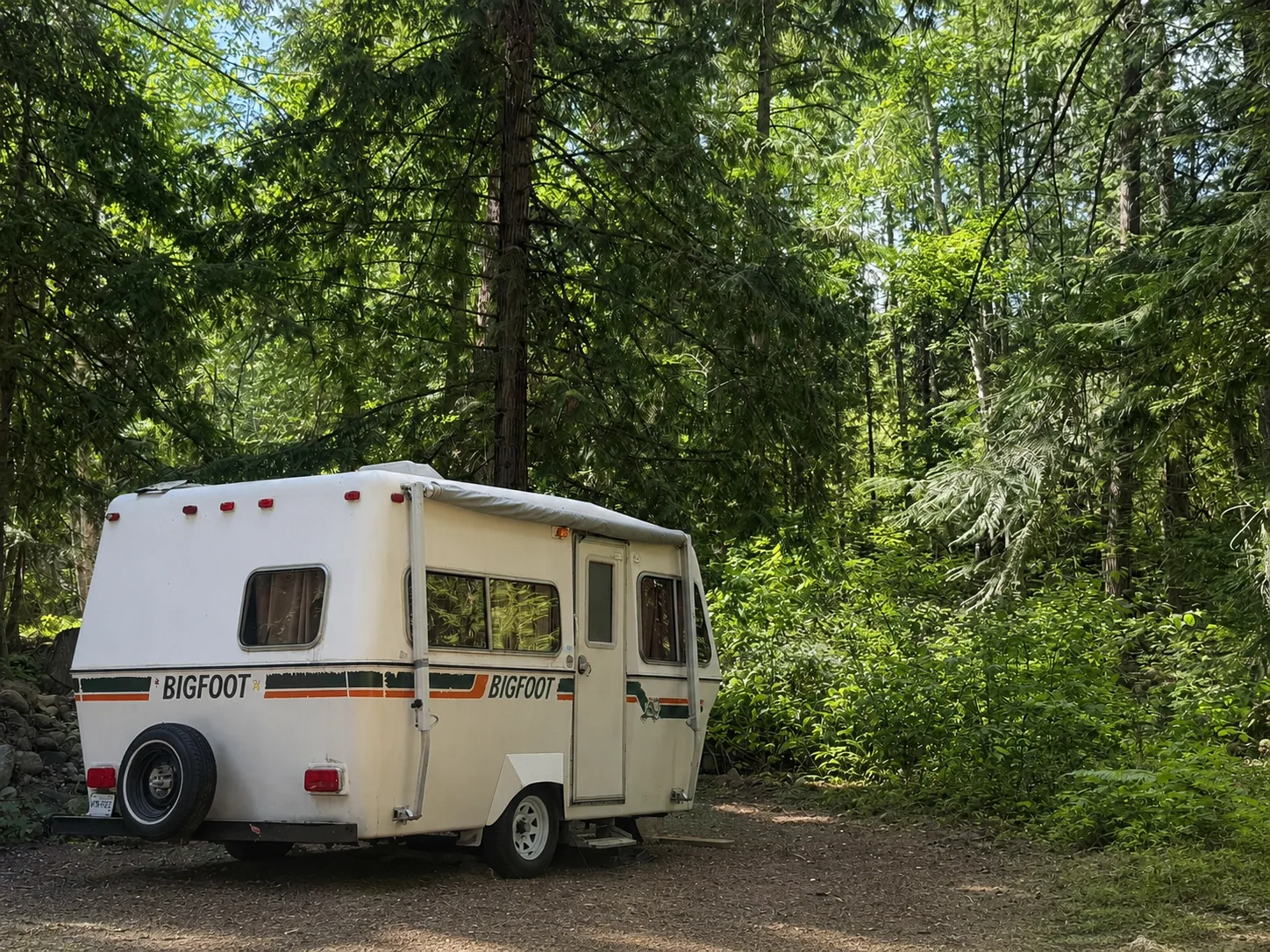 A Bigfoot trailer parked at a forested RV site